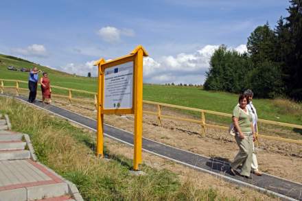 Tablica Projektu i piesi idący ścieżką pieszo-rowerową